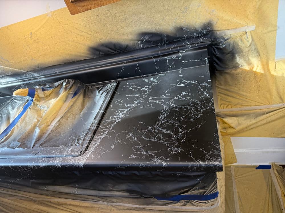 Black marble effect painting process on a countertop, with protective coverings in place.