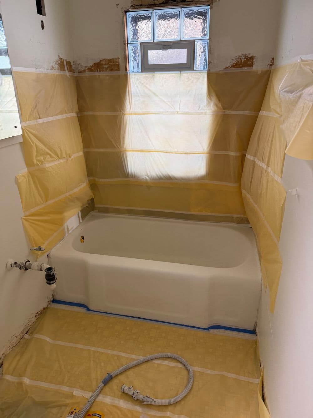 Bathroom renovation in progress with a bathtub, protective barriers, and construction materials.