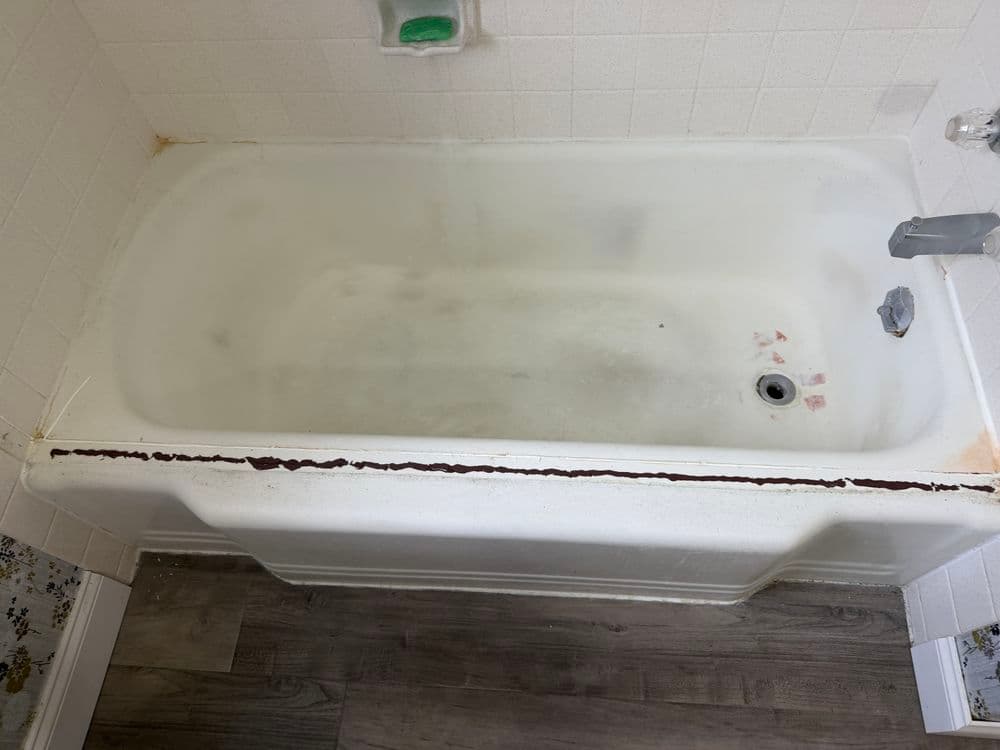 Old bathtub showing signs of wear with visible stains and rust along the edge.