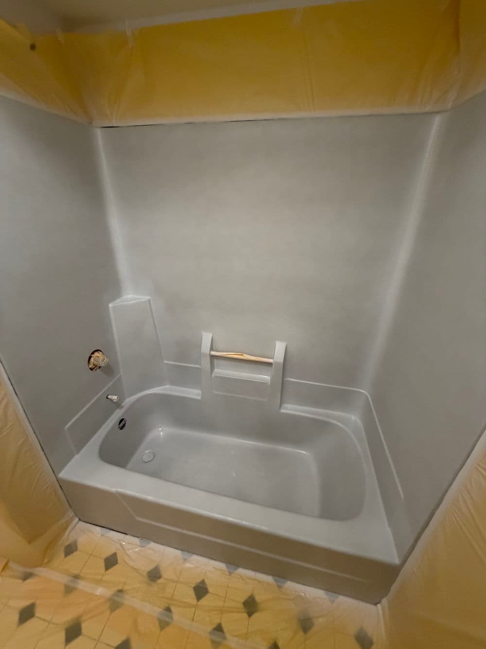 Bathroom renovation with a newly installed gray bathtub and protective coverings in place.