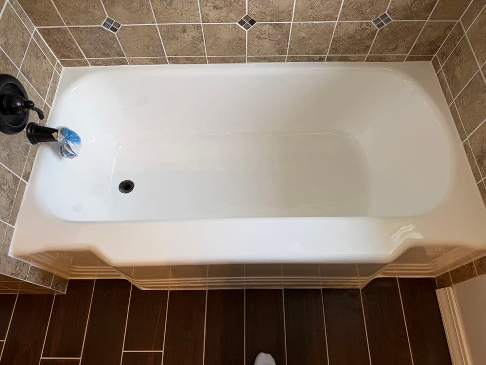 Modern white bathtub with elegant tile surround and black faucet in a stylish bathroom.