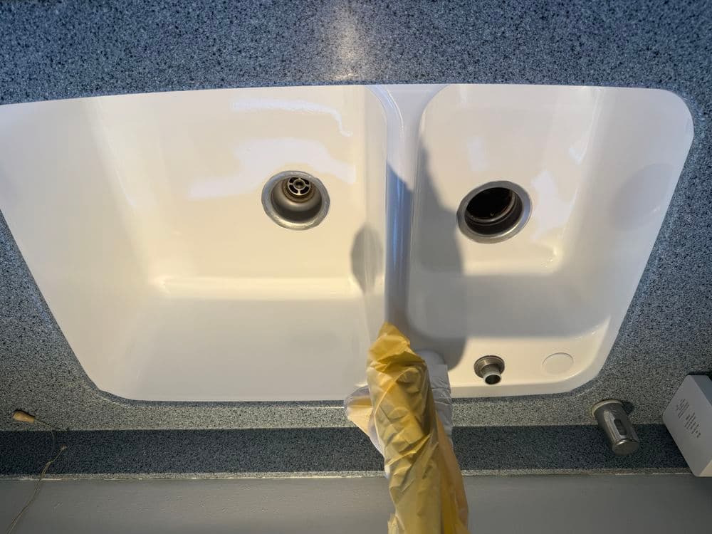 White double sink with a granite countertop and plumbing fixtures visible.
