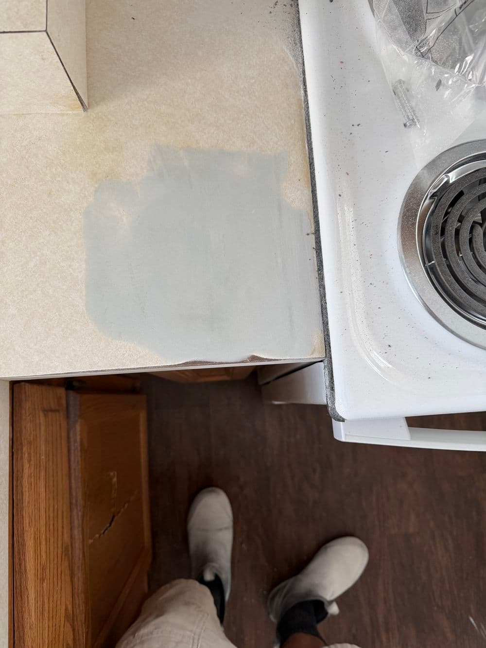 Kitchen countertop with gray patch and stove in view, showing a repair in progress.