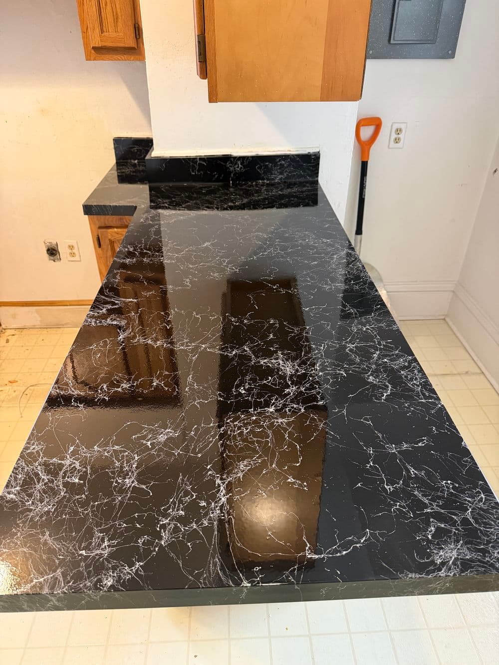 Black marble countertop with white veining, modern kitchen design, and wooden cabinets.