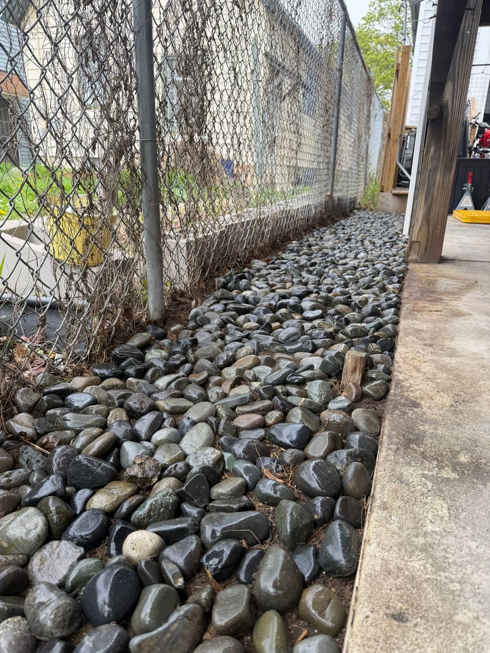 Pea gravel landscaping along a chain-link fence, enhancing outdoor space aesthetics.
