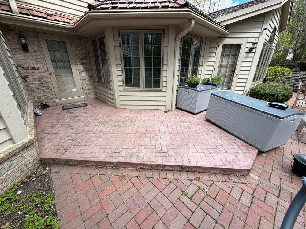 Paved patio with modern planters and a chest freezer near a house exterior.
